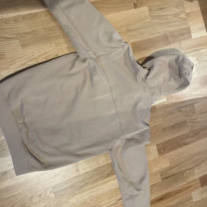 Beige hoodie från Sweet Skates - Säljer en beige hoodie från Sweet Skates. Den har en stor ficka framtill och justerbar huva med dragsko. Perfekt för en avslappnad stil.