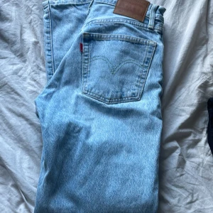 Ljusblå jeans från Levi's - Säljer ett par klassiska ljusblå jeans från Levi's med den ikoniska läderpatchen och röda etiketten. Perfekta för en avslappnad stil. De har en normal passform och är tillverkade i slitstarkt denim.