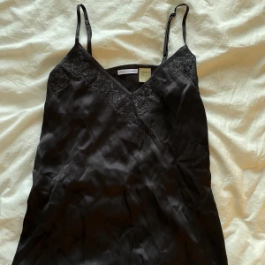 Linne från Laura Clement - Snyggt mörkgrått linne från Laura Clement med spetsdetaljer vid halsringningen. Justerbara axelband för bästa passform!!🖤Passar XS/S