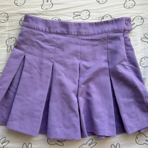 Lila kjol från H&M Divided - Säljer en söt lila kjol från H&M Divided. Kjolen har en kort längd och veckad design som ger en fin volym. Perfekt för att lägga till en färgklick i garderoben!