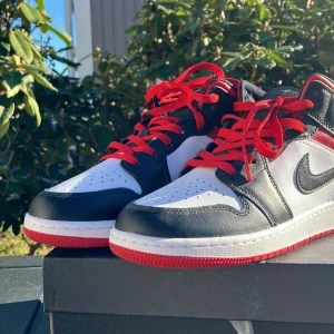 Nike Air Jordans i svart, vitt och rött - Snygga Nike Air Jordans i klassisk svart, vit och röd färgkombination. Skorna har en ikonisk design med snörning och den välkända Air Jordan-loggan. Perfekta för dig som vill ha stil och komfort i ett.