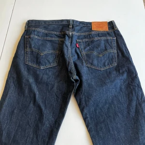 Levi's 501 jeans i mörkblå denim - Klassiska Levi's 501 jeans i mörkblå denim. Dessa jeans har en rak passform och är tillverkade av högkvalitativt denim. Perfekta för en tidlös stil. Använt dom mycket men fortfarande jätte bra skick