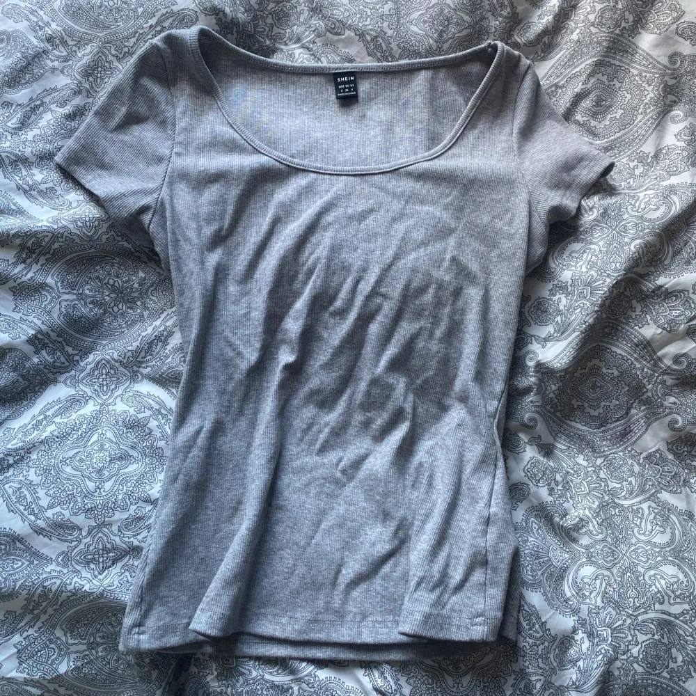 Säljer en grå ribbad t-shirt från Shein. T-shirten har en rundad hals och korta ärmar, inga defekter och använd ett fåtal gånger. Väldigt bekväm. T-paidat.