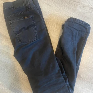 Svarta jeans från Nudie Jeans - Snygga svarta jeans från Nudie Jeans i modellen Lean Dean. Tillverkade av 98% ekologisk bomull och 2% elastan för en bekväm passform. Klassisk design med fem fickor och knappgylf. Perfekta för en stilren look.