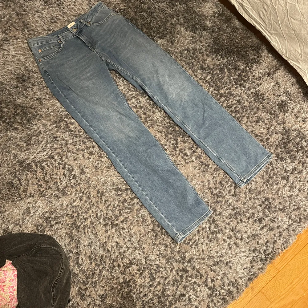 Säljer ett par klassiska blå jeansbyxor med normal passform. De har en traditionell femficksdesign och är tillverkade i denim. Perfekta för en avslappnad stil. De är i modellen straight och från Nelly. De är aldrig använda och jag säljer dom pågrund av att de är lite för stora.. Farkut & Housut.