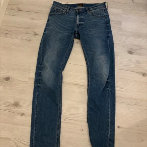 Blå jeansbyxor från Levis - Snygga blå jeansbyxor från Levis med klassisk femficksdesign och knappgylf. Perfekta för en avslappnad stil. De har en smal passform och är tillverkade i slitstarkt denim.