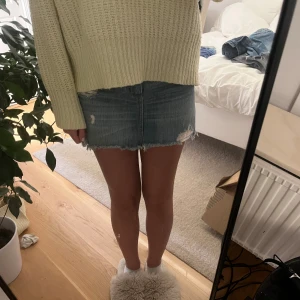 Jeanskjol från Hollister - Säljer en snygg jeanskjol från Hollister med fem fickor och slitna detaljer. Kjolen har en klassisk blå denimfärg. Den är kort och har en rå kant nertill, något längre där bak. Passar perfekt till en stickad tröja eller en enkel t-shirt. Den är 36 cm i midjemått och 33 cm lång!