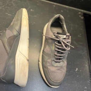 Axel Arigato skor - Snygga grå sneakers från Axel Arigato med en stilren design. Skorna har snörning och en bekväm sula. Perfekta för en casual look. Storlek 44