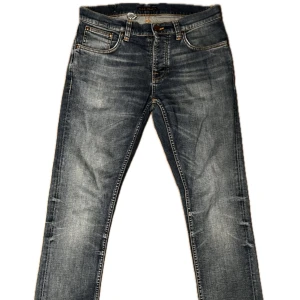 Blå jeans från Nudie Jeans - Snygga blå jeans från Nudie Jeans med en klassisk femficksdesign och orange sömmar. Jeansen har en straight passform och är tillverkade i slitstarkt denim. Perfekta för en avslappnad stil. Ihopsytt hål på insidan vid midjebandet, men inte synligt på utsida. 