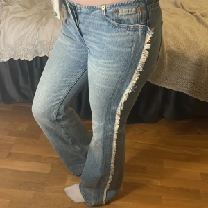 Blå jeans med fransdetalj - Snygga blå jeans med fransdetaljer längs sidorna. Lågmidjade jeans i modellen ”Nova” från Weekday. Endast provade ej använda. Långa i benen.