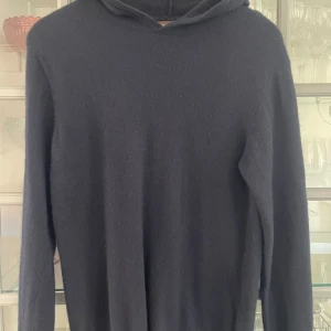 Svart hoodie från Oscar Jacobson - Säljer en stilren svart hoodie från Oscar Jacobson. Tröjan är tillverkad i en mjuk blandning av ull, viskos och kashmir, vilket gör den både bekväm och lyxig. Perfekt för kyligare dagar. (Passar storlek S)