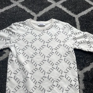 Vit tröja från Valentino - Säljer en stilren vit tröja från Valentino med ett elegant mönster av logotypen över hela plagget. Tröjan har långa ärmar och en rund halsringning. Perfekt för en trendig look. Köpt från farfetch 2022 men har varit för liten så har inte kunnat ha på mig tröjan. Den har en liten söm som är öppen vid kragen därför jag säljer den för så bra pris. Skriv för mer info om intresserad😁 storlek s men passar xs