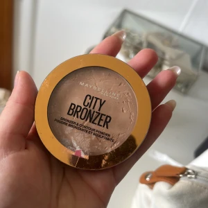 City Bronzer från Maybelline - City Bronzer från Maybelline i nyansen Light Warm 150. Perfekt för att skapa en naturlig solkysst look. Kompakt förpackning med genomskinligt lock.. har aldrig använt den dock har locket gått sönder därav är det ”märken” på bronzern 