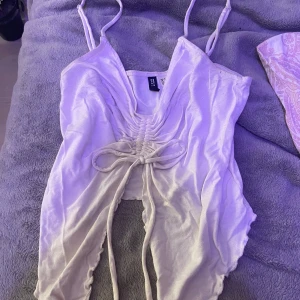 Vit fjärils topp - Säljer en stilren vit ärmlös topp med smala axelband och snygg snörning framtill. Perfekt för en somrig look