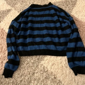 Blå och svart randig stickad tröja - Säljer en stickad tröja med breda blå och svarta ränder. Tröjan har lång ärm, ribbade muddar och en lite croppad passform. Perfekt för dig som gillar en chill och trendig stil. Tröjan kommer från h&m i storleken S. Bara att fråga om det är något!!