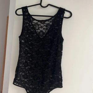 Svart spets body från Vero Moda  - Säljer en svart spets body med blommigt mönster. Toppen har v-ringning i ryggen men den går även att använda åt båda håll. Den är från Vero Moda och är aldrig använd bara provad. 
