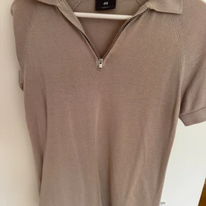 Beige pikétröja med half zip från H&M - Väldigt snygg beige pikétröja från H&M med kort ärm och krage. Tröjan har en stilren half zip-dragkedja framtill och är tillverkad i ett mjukt stickat material. Perfekt för dig som gillar en clean och modern look. Säljer för 179kr. Ingen storlek men passar nog runt 170-175cm