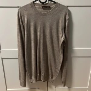 Beige merinoulltröja Oscar Jacobson M - Snygg beige tröja från Oscar Jacobson i mjuk merinoull. Klassisk rund halsringning och långärmad modell.  Tillverkad i Italien och passar lika bra till jeans som till chinos. Säljs för att den är för liten för mig
