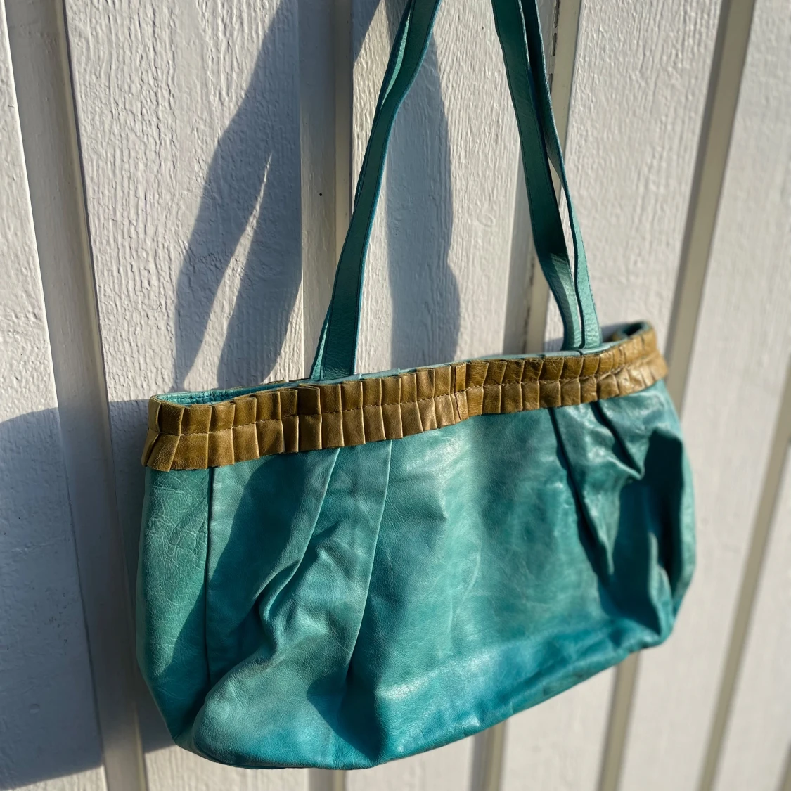 Turkos axelväska i skinn med detaljer