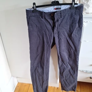 Mörkblå slim fit chinos 33/30 - Snygga mörkblå chinos i slim fit-modell med klassiska fickor fram och bak. Byxorna är tillverkade i bomull med lite elastan för extra komfort och stretch. Perfekta för dig som gillar en stilren och smal passform.