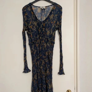 Klänning Noa Noa - Supersöt, fin klänning från Noa Noa i tunn blommigt mönster i beige, orange och grönt. Klänningen har lång ärm och lätt rynkad struktur. Man ser igenom, men ha något under om du inte vill visa. Tror den passar XS-M. Stretchig.  Mina varor brukar oftast vara uppe under en begränsad tid, sen tas de bort och kommer då inte tillbaka. Hör gärna av er innan köp av fler varor, kan ordna paketpris. 🌞