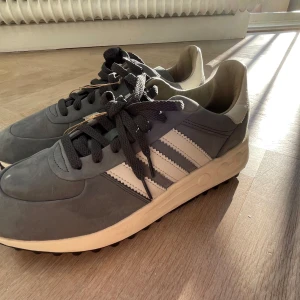 Adidas LA trainers lux - Snygga grå sneakers från Adidas med klassiska vita ränder på sidorna och svart snörning. Skorna har en beige sula med coola detaljer och en retroinspirerad look. Ovandelen är i mocka och skinn, perfekt för dig som gillar stilrena och tidlösa sneakers. Tveka inte att höra av dig!!!