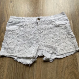 Lågmidjade spets shorts  - Snygga vita shorts med spetsdetaljer framtill och fransig kant nertill. 