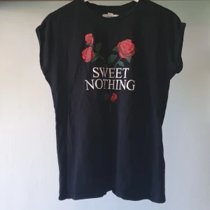 Svart t-shirt med rosor från NA-KD - Svart t-shirt i 100% bomull från Josefin Ekström for NA-KD. Framsidan har tryck med röda rosor och texten 'SWEET NOTHING' i vitt. Modellen är ärmlös med avslappnad passform, perfekt för en cool och trendig look. 100% Bomull ❤️ Använd hemma + när jag gick på Taylor Swift's Eras Tour förra året så i bra skick! 