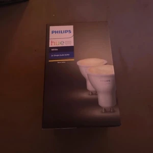 Led-lampor - Bilderna visar en förpackning med Philips Hue smarta LED-lampor (2x GU10, White). Detta är ingen bok, utan smarta ljuskällor som styrs trådlöst och passar för dig som vill ha modern belysning hemma. Perfekt för dig som gillar teknik och smarta hem.