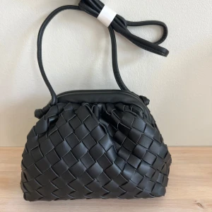 Svart flätad dumpling bag från BOW19 - En super fin HELT ny svart flätad väska från BOW19. Väskan gör din look komplett och den funkar till precis allt!! Sving snygg och är helt slutsåld på BOW19 hemsida!!  Aldrig använd, kvitto finns och jag har även kvar påsarna som jag fick den i. Jag säljer den då jag fick 2 i födelsedagspresent. Tveka inte på att höra av dig om du har mer frågor! 