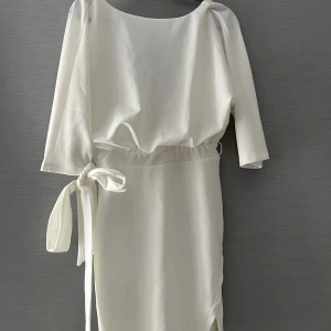 Vit omlottklänning med knytband - Klänning köpt för studenten som aldrig kom till användning. Fin passform och perfekt nu till sommaren. Passar även som klänning till konfirmation