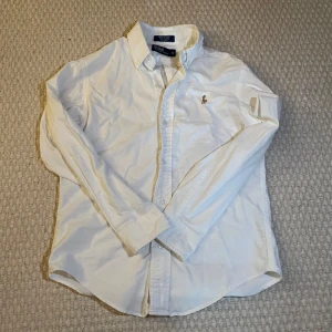 Ralph Lauren skjorta - En vit fräsch ralph lauren skjorta som passar perfekt på sommaren!🤍☀️Den är i jätte bra skick bara lite skrynklig men kan stryka den innan jag skickar. Är i storlek y12 så passar bra på nån som är runt 150-155 cm. Priset är inte hugget i sten, bara höra av sig om jag missat nått eller har några frågor🤍