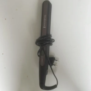 Remington plattång - Säljer en svart plattång från Remington med sladd och smal design. Perfekt för att styla håret rakt eller skapa lockar. Plattången har en mörkbrun panel och enkla knappar på sidan för att justera värmen. Model S-6505 nypris runt 500-600kr