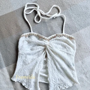 🤍✨Vit spetsig croppad halterneck topp med snäckdetaljer!🤍✨ - Superfin vit croppad halterneck topp i spets med snäckor och små silverfärgade detaljer längs kanten!🤍 Toppen har omlottliknande framsida och knyts i nacken. Perfekt för sommaren och strandhäng!🤍✨🫶🏻 Toppen är endast testad, aldrig använd. Märket är ” Breezaya ”. Toppen är köpt för runt 100 kr. 