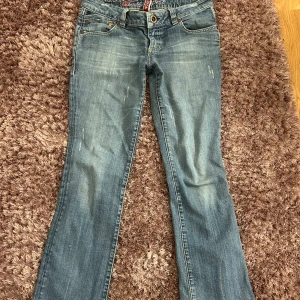 Blå bootcut lowwaist jeans från 7 For All Mankind - Snygga blå jeans från 7 For All Mankind med bootcut, låg midja och snygga fickor. Tror att de skulle passa perfekt på någon runt 162, men tyvärr är jag för lång så de passar inte mig. Broderad logga på bakfickan och röd etikett i midjan. Pris går att diskutera och fler bilder kan skickas!💞