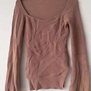 Beige ribbad långärmad topp - Säljer en beige ribbad långärmad topp med bred, djup urringning. Snygg passform och stretchigt material som sitter tajt mot kroppen. Perfekt att styla med jeans eller kjol.