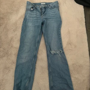Blå jeans från Gina tricot - KAN GÅ NER I PRIS VID SNABB AFFR!! Säljer ett par klassiska blå jeans från Gina tricot i modellen perfect jeans, modellen är slut såld och går inte att köpa mer. Många känner igen dessa jeans pga av att saga stq hypade upp dom. Modellen har raka/ utsvängda ben och en snygg sliten detalj med hål på ena knät. 