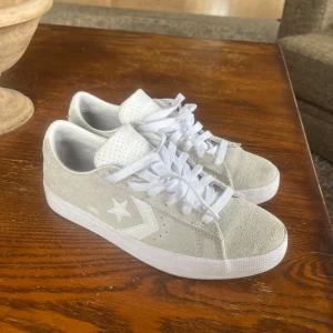 Gråa Converse sneakers i mocka - Säljer ett par stilrena gråa Converse sneakers i mocka med vit sula och klassisk stjärndetalj på sidan. Skorna har snörning och perforerad plös för extra ventilation. Perfekta för en avslappnad och trendig look.