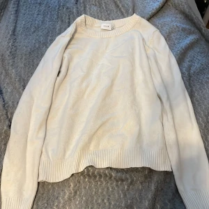 Vit stickad tröja från Vila - Säljer en enkel och stilren vit stickad tröja från Vila i storlek S. Tröjan har rund halsringning, långa ärmar och ribbade muddar vid ärmslut och nederkant. Perfekt för lager-på-lager under kyligare dagar.