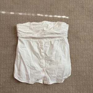 Vit tubtopp med knappar från Zara - Säljer en vit tubtopp från Zara i storlek L. Supersnygg men tyvärr passar den inte och endast använd  två gånger!