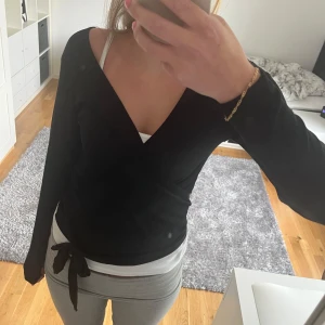 Svart omlottopp med knytband - Jätte gullig omlott kofta med rosetknytning. Använd fåtal gånger. Är i storlek M men skulle mer säga att de är en S. Tryck gärna på köp nu och tveka inte vid eventuell fråga🫶🫶