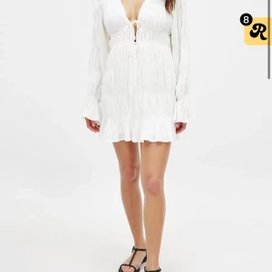 slutsåld vit Klänning Moa Matsson x NAKD - Helt oanvänd Superfin vit kortklänning med v-ringning och knyt framtill. Klänningen har långa ärmar med volang. Från Moa Matssons kollektion tillsammans med NAKD. Storlek 34