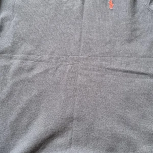 Mörkt blå pikétröja från Ralph Lauren - Säljer en klassisk grå pikétröja från Ralph Lauren med den ikoniska loggan broderad i rött på bröstet. Tröjan är tillverkad i 100% bomull och har en tidlös design som passar perfekt till många tillfällen. På bilden syns inte men den är mörkt blå helt ny