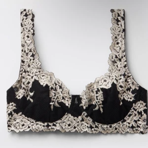 Svart och vit spets BH  - Säljer en snygg svart bh med via spetsdetaljer. Bh:n har breda axelband och är perfekt för att ge en lyxig känsla till din outfit. Spetsen ger en romantisk och trendig look. Har aldrig använt💞