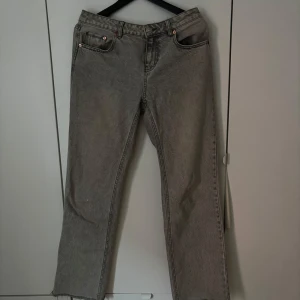 Grå jeans från Stradivarius - Säljer ett par grå jeans från Stradivarius med raka ben och råa benslut. Klassisk femficksmodell med normal passform och mellanhög midja. Perfekta till vardags för en avslappnad stil.