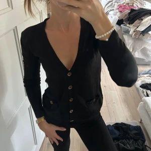 Svart kofta med knappar från Gina Tricot - Säljer en svart kofta från Gina Tricot i storlek XS. Koftan har v-ringning, långa ärmar, två fickor framtill och snygga knappar💕