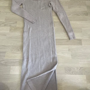 Beige ribbad långklänning från SHEIN - Säljer en beige ribbad långklänning från SHEIN med lång ärm och rundad halsringning. Klänningen har en tight passform och är tillverkad i ett mjukt, stretchigt material som sitter snyggt på kroppen.