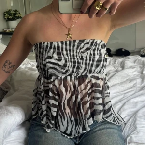 Tubtopp med zebramönster - Zebramönstrad tubtopp med knyt framtill. Toppen är axelbandslös och har en lätt transparent, flowy nederdel. Perfekt att vända på toppen så baksidan är framtill, super snyggt (bild 1 & 4)🤌🏼