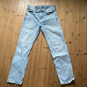 Ljusblå relaxed fit jeans från H&M - Säljer ett par ljusblå jeans från H&M med relaxed fit och raka ben. Jeansen har dragkedja och knapp i midjan. Perfekt för en avslappnad look. Lite trasiga i benslutet (bifogad bild) men är inget som påverkar looken