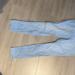 Ljusblå jeansbyxor från H&M - Ljusblå jeansbyxor från H&M i klassisk femficksmodell. Byxorna har normal passform och raka ben, med gylf och knapp framtill. Perfekta till vardags för en avslappnad stil.